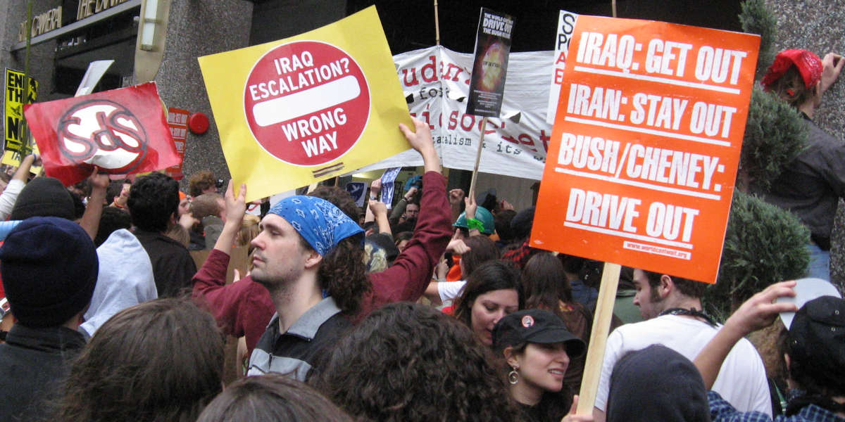 A mass of protesters holding placards outside a building
