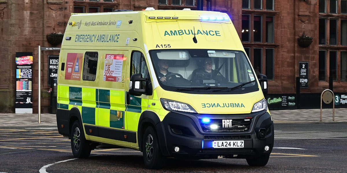 A photograph of a British ambulance with its lights on
