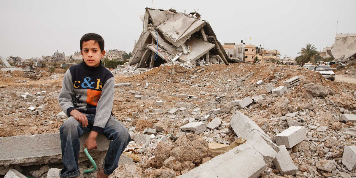 A young boy sitting amidst rubble in Gaza