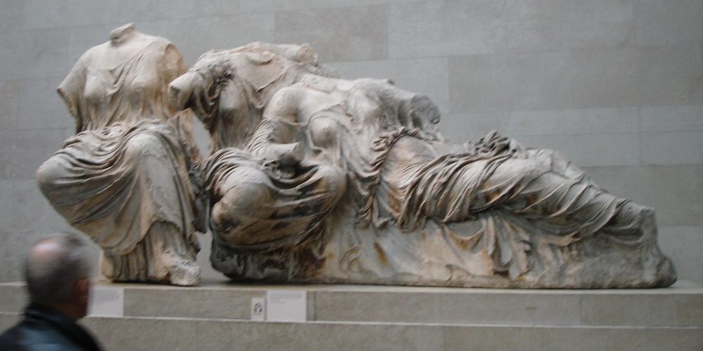 A person looks at a headless classical statue in the British Museum