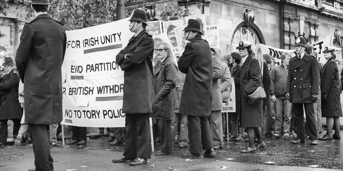 A black and white photograph of a march against the partition of Ireland, showing marchers holding banners and flanked by police