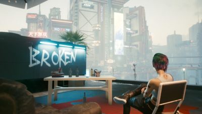 Screenshot from Cyberpunk 2077 showing a character from the game sitting in front of a futuristic cityscape and the word 'broken' graffitied onto a wall