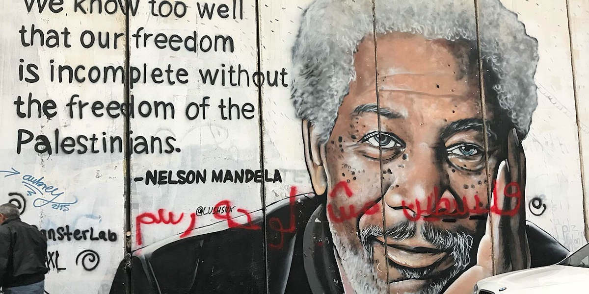 A mural of Nelson Mandela painted on the West Bank border wall alongside a quote of his