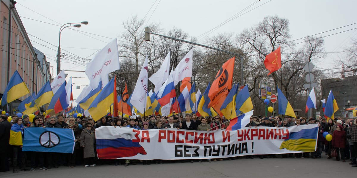 A large rally of marchers holding Russian and Ukrainian flags and messages of peace
