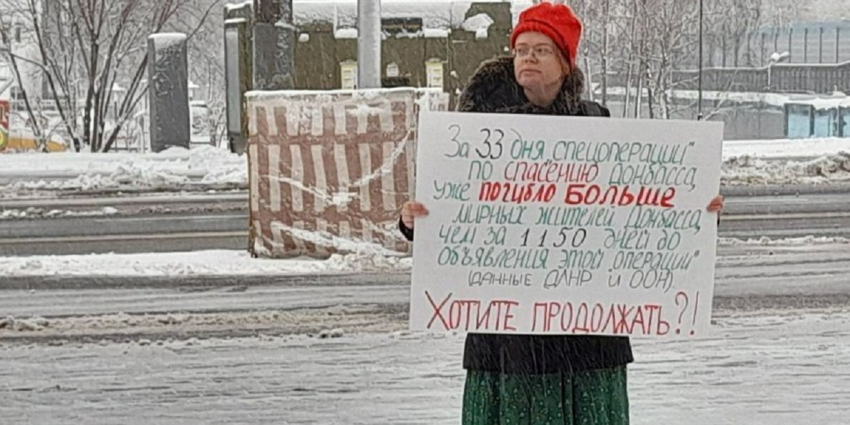 A woman stands in the snow with a placard