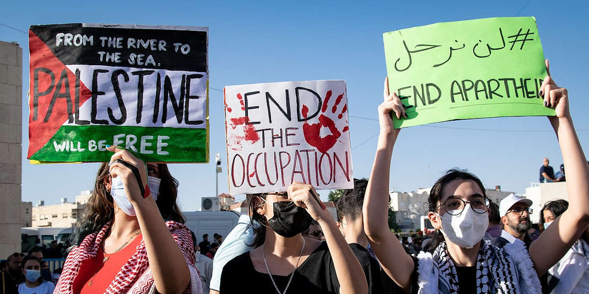 Protestors holding up pro-Palestinian signs calling for a boycott of Israeli goods