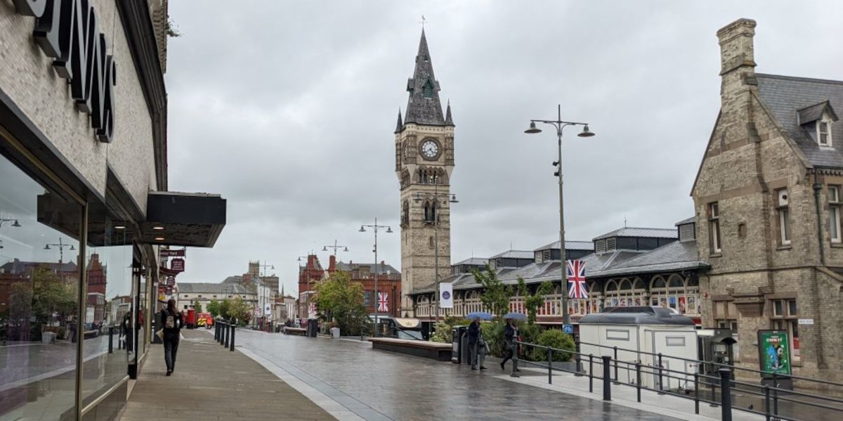 An English high street with a town hall clock tower and rain-washed streets