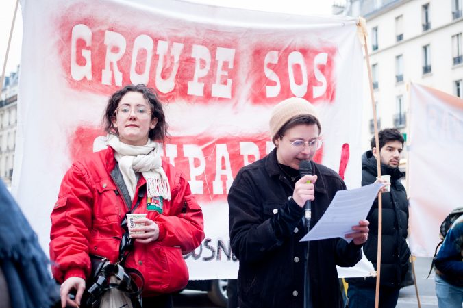 Two women speak into microphones at a protest