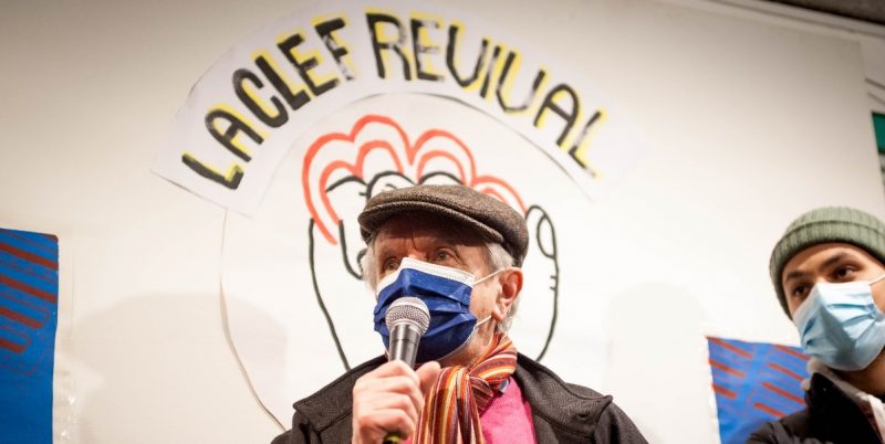 A man wearing a face mask speaks into a microphone