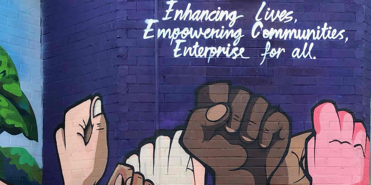 Mural showing clenched fists and the words 'Enhancing lives, empowering communities, enterprise for all'