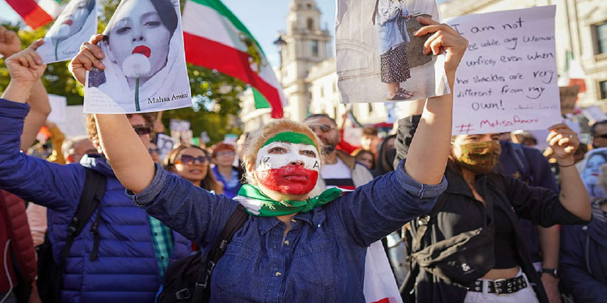 At the head of a protest march, a woman with her face painted in the colours of the Iranian flag holds up a photo of Mahsa Amini