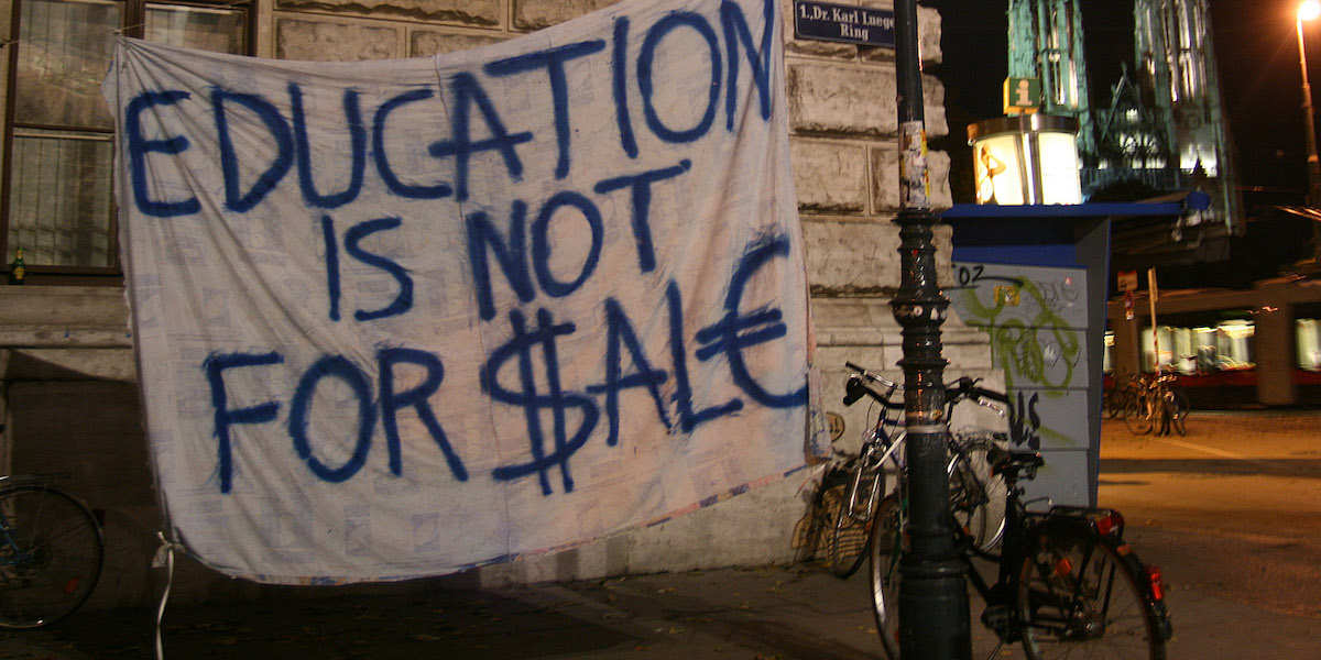 A protest banner outside a university building in Vienna reads 'education is not for sale' with the S and E replaced by dollar and euro symbols