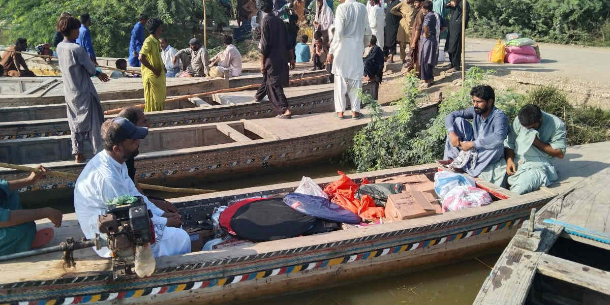 People in long, narrow river boats loaded with boxes and bags