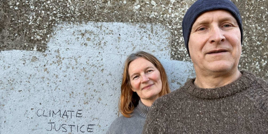 Ci and Darcy pose next to a wall that has 'Climate Justice' written on it