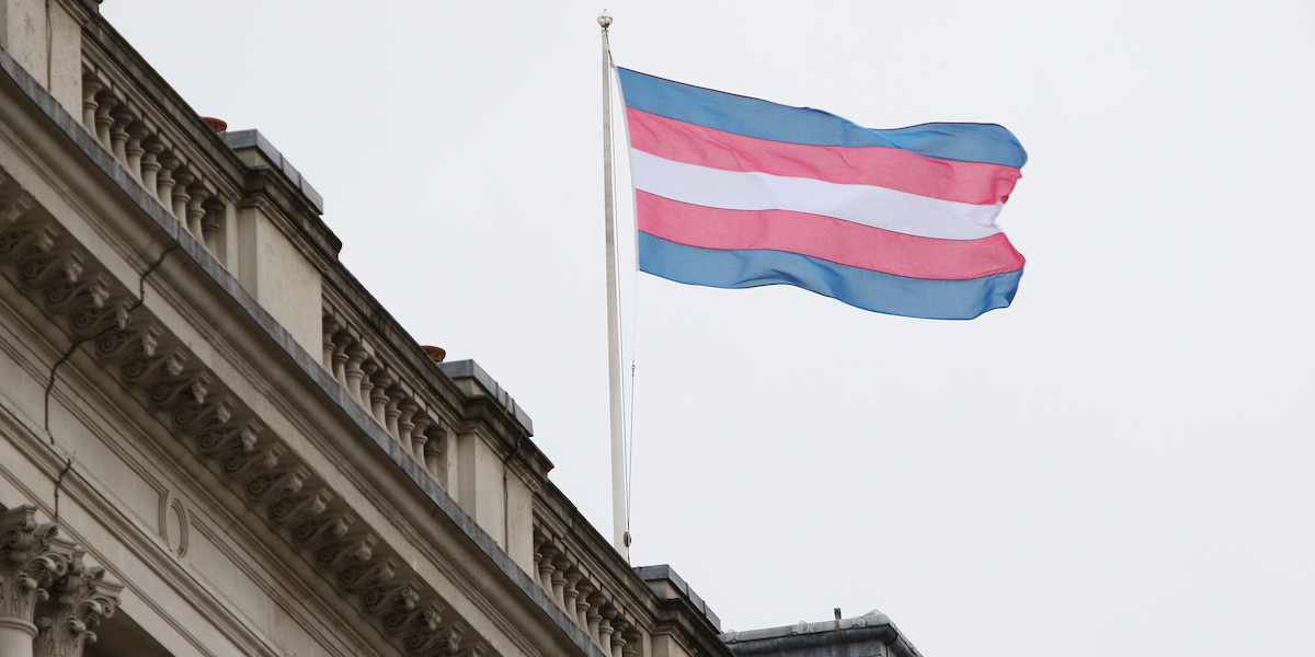 The Transgender Pride Flag – white, blue and pink stripes – flies at on a pole over a grand looking building