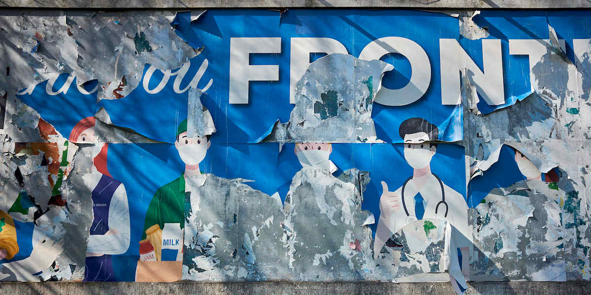 A torn billboard poster showing key workers in face masks CREDIT:JOHN PERIVOLARIS