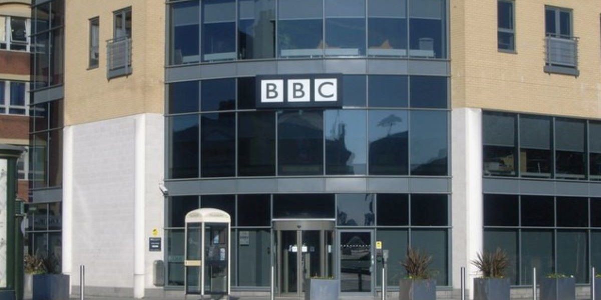 A glass fronted building with the BBC logo above its entrance