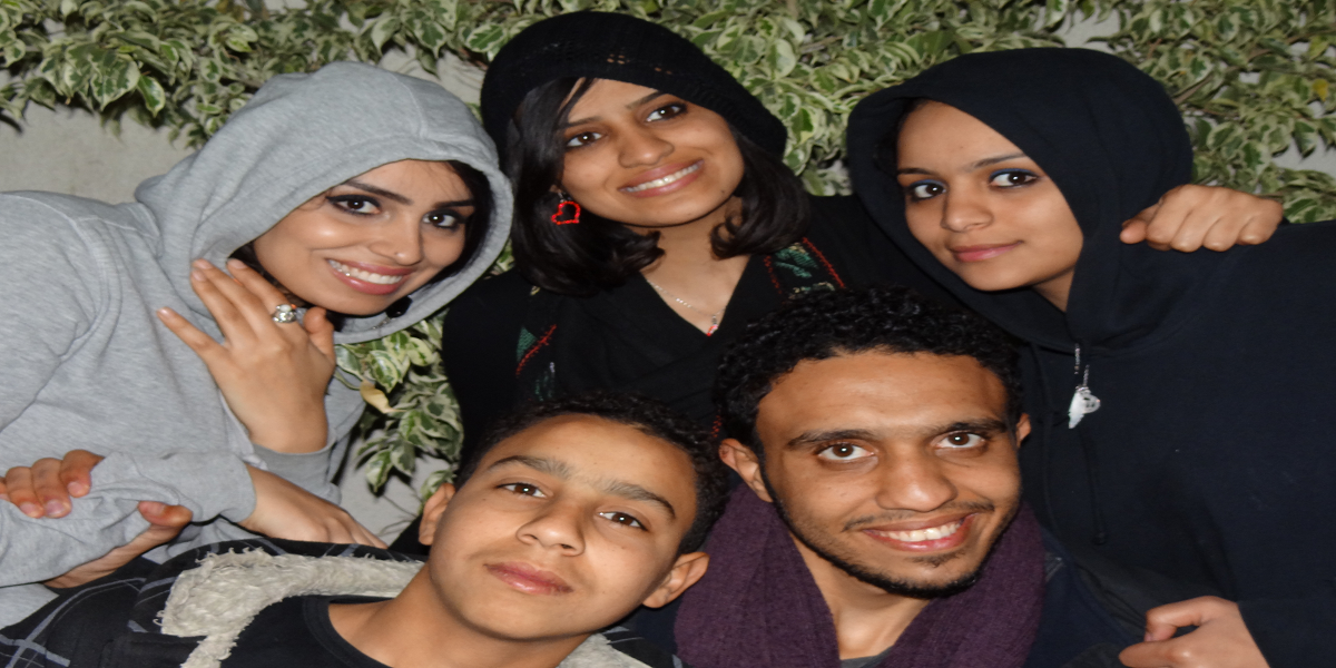 Shahd (top left) and her four siblings, smiling and putting their heads together against a leafy background