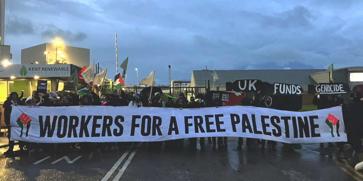 Protesters outside a factory building hold a banner that reads: 'Workers for a free Palestine' and placards reading 'UK funds genocide'