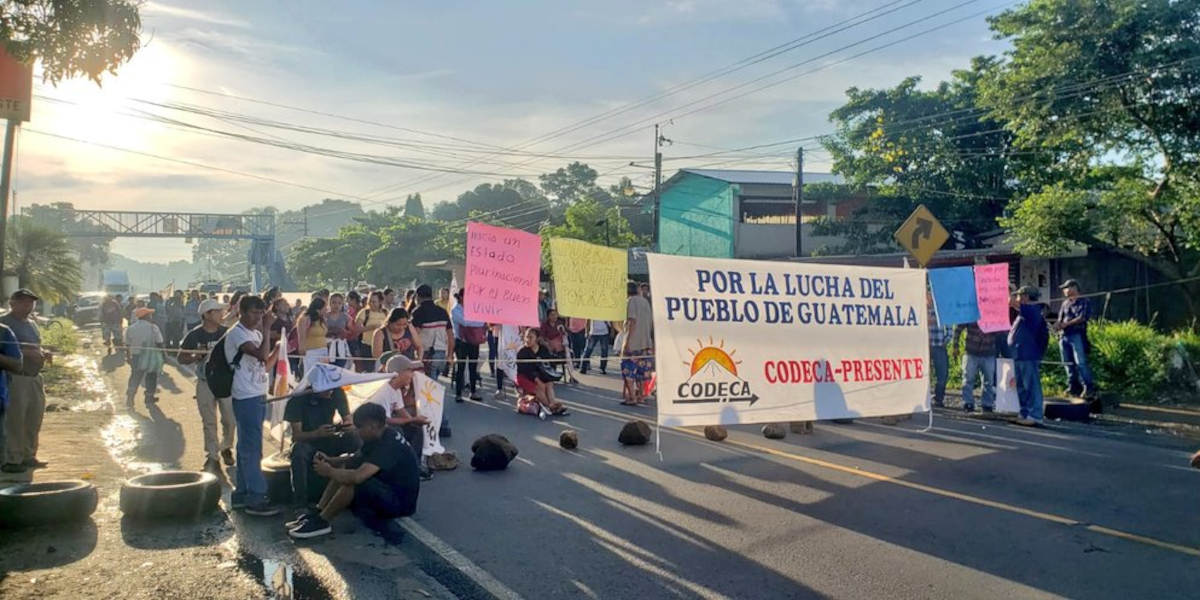 Sun rises over a road block filled with people, rocks and pro-democracy banners