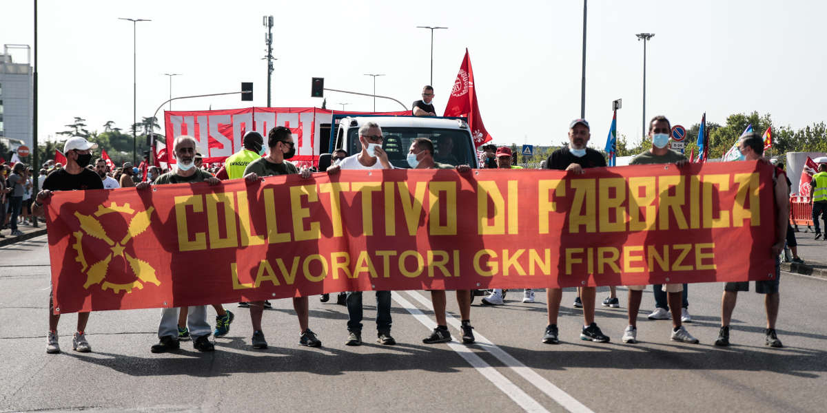 A group of maching protesters with a red banner reading 'Colletivo di Fabbrica: Lavoratori GKN Firenze'