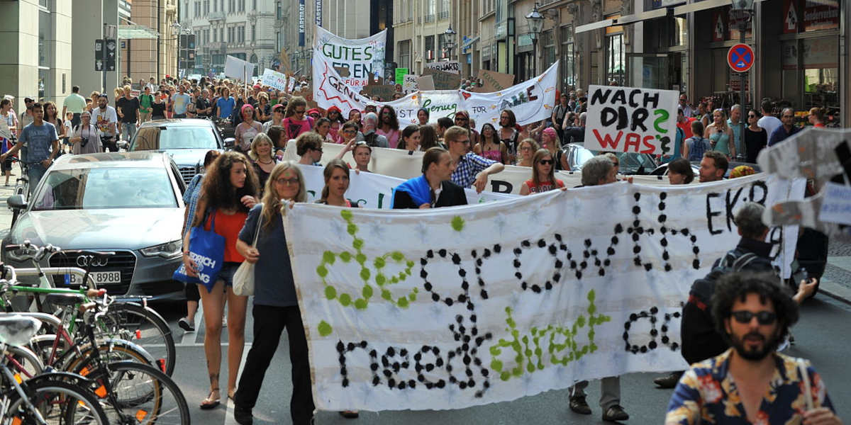 A climate protest in Germany displaying a large pro-degrowth banner in German
