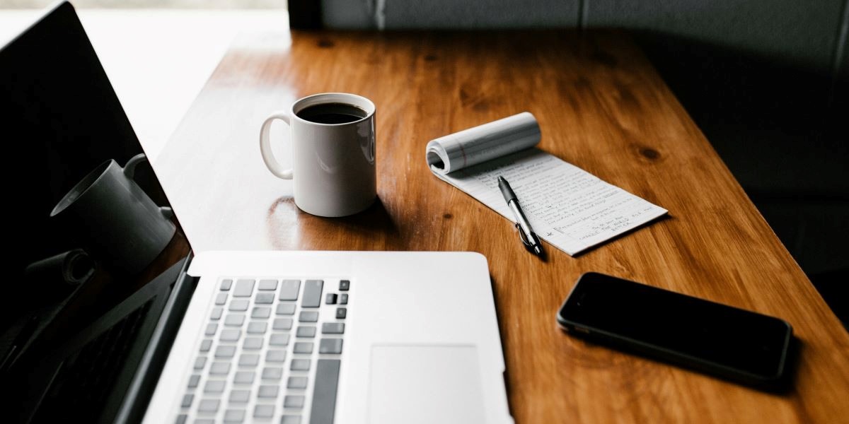 Writing - featuring laptop, phone, notebook, pen and coffee mug on table