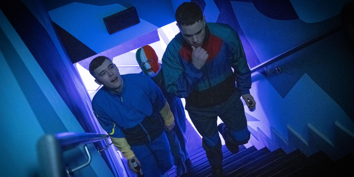 Three men in tracksuits walk up a staircase