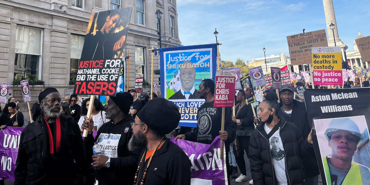 Protestors in central London bearing signs and placards with the images of people who were killed by the police