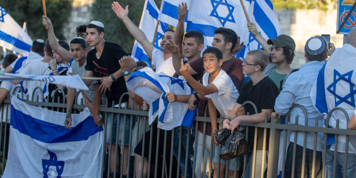 Israeli settlers waiving flags from behind a barrier