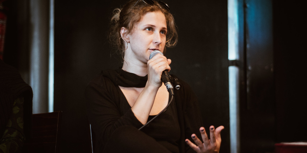 Maria Alyokhina, seated and speaking into a microphone at a press conference