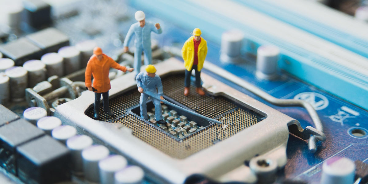 Four plastic miniature workers depicted as working on top of a circuit board