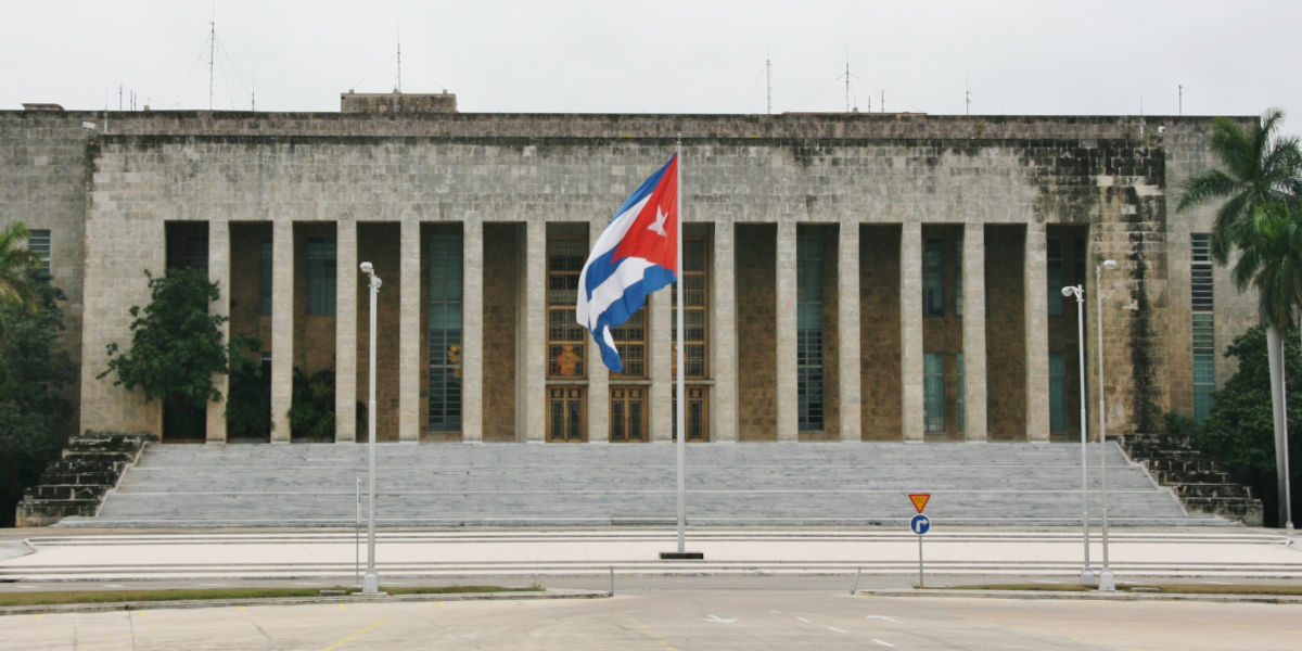 The exterior of the headquarters of the Communist Party of Cuba in Havana, with a flagpole displaying the Cuban flag in front of it