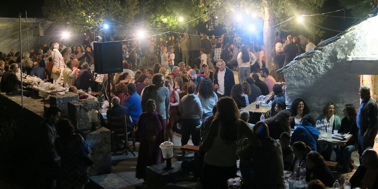 A night time gathering of people under lights and trees