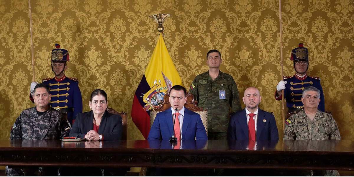 Ecuadorian President Daniel Noboa, sat at a table with officials and military figures either side of him, announcing the construction of new high security prisons