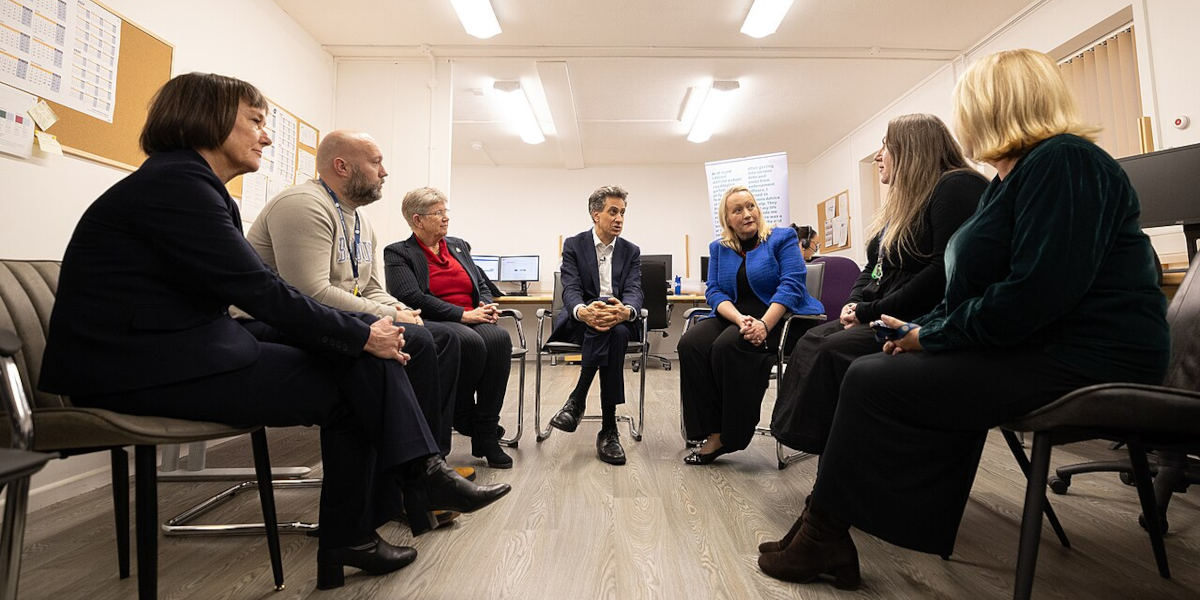 Energy Security and Net Zero Minister Ed Milliband and Welsh Minister Jo Stevens sitting in the centre of a semicircle, with volunteers from Cardiff & Vale Citizens Advice Bureau on either side of them